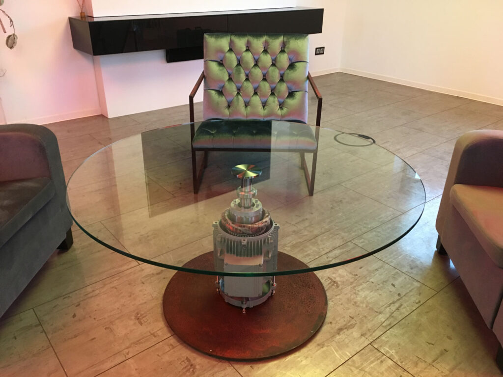 Moderner Glastisch mit Elektromotor als Design-Standfuß