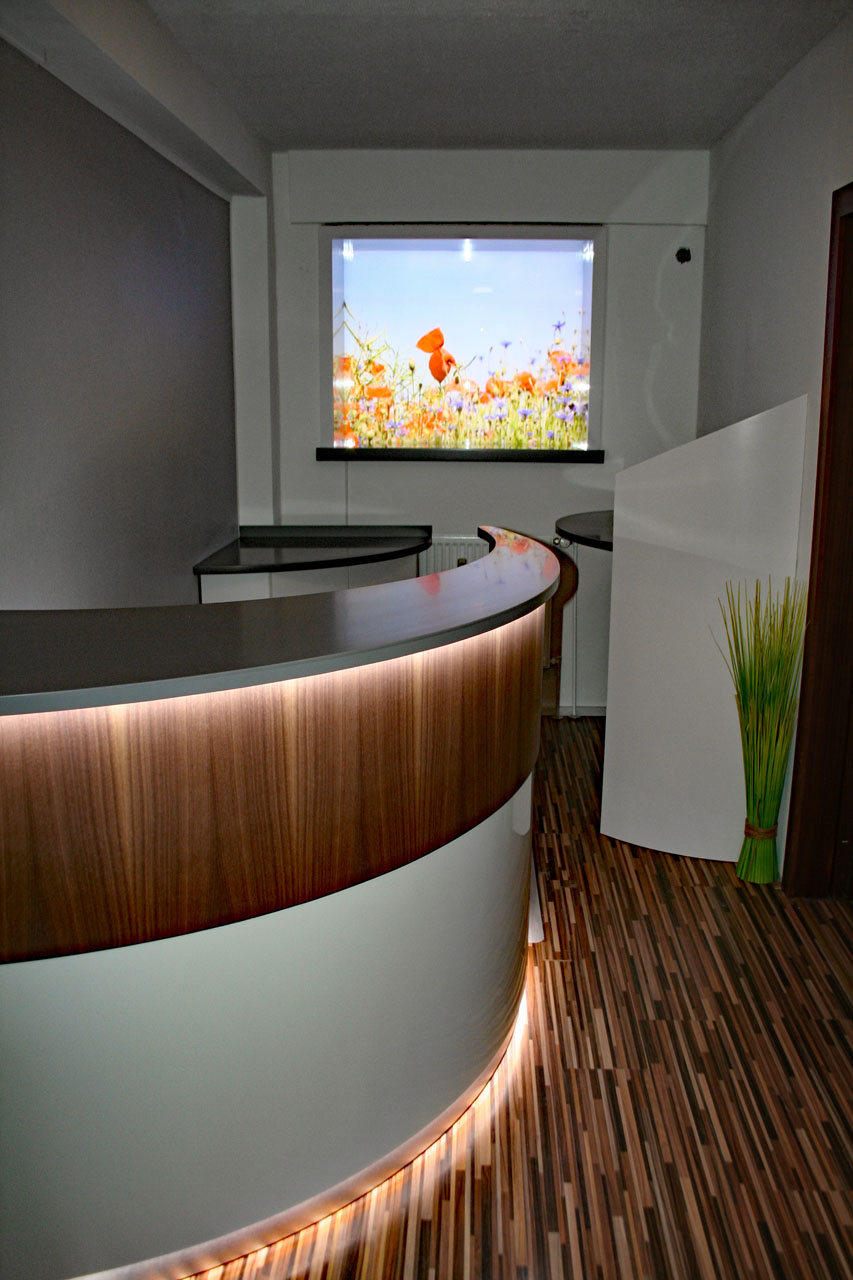 Empfangstresen einer Physiotherapiepraxis in Springe mit beleuchteter Blumenwiese und indirekter Beleuchtung.