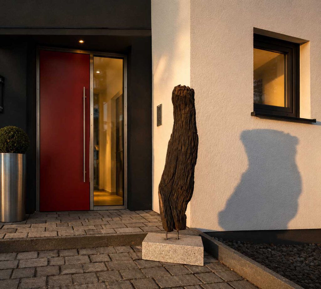 Holzskulptur Wächter aus Mooreiche vor einem Einfamilienhaus